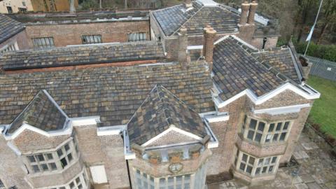 Hopwood Hall, a large historic stately home is seen from an aerial view of the large brick building