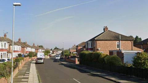 Ruskin Avenue. There are two-storey, semi-detached houses on both sides of the street, with parked cars and a van.