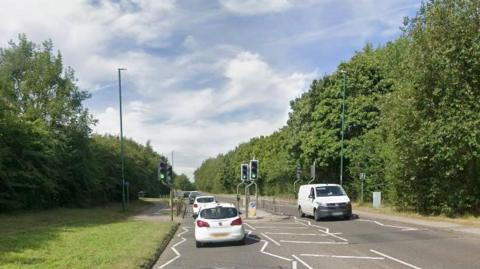 Streetview image of Woodhouse Way, Nuthall, a tree-lined single carriageway road with a pedestrian crossing in the foreground