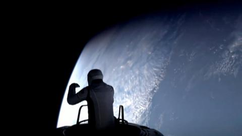 Isaacman leaning out of capsule silhouetted against Earth