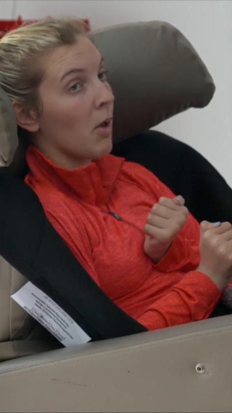 Blonde teenage girl wearing a red top sat in a high-backed chair