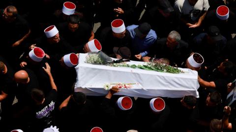 A coffin is carried by members of the Druze community