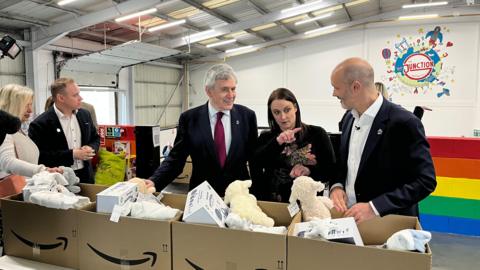 Ex-PM Gordon Brown with The Junction's Beth Major and John Boumphrey from Amazon at the new Multibank centre in Teesside. They are looking at cardboard boxes filled with 