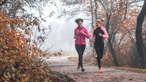 Shot of two young sportswomen running in nature on a foggy morning.