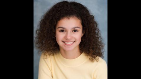 A girl in a yellow jumper. 