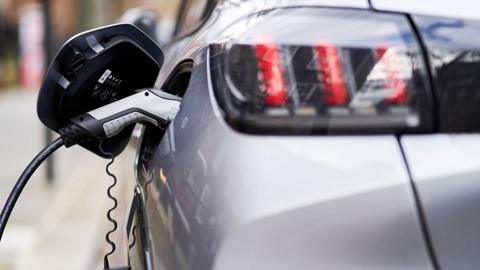 Rear view of an electric charger plugged into a silver car 