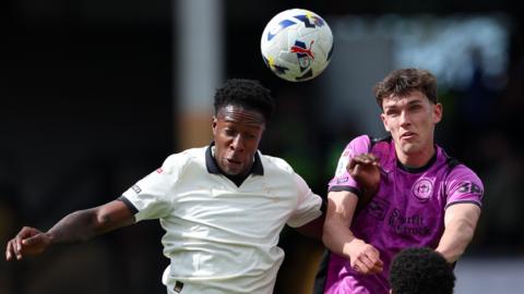 Liam Gordon of Port Vale and Dara Costelloe of Wigan Athletic compete in the air