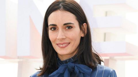 Melisa Sozen wears a blue blouse with a bow at a photocall during the Canne film festival in 2018