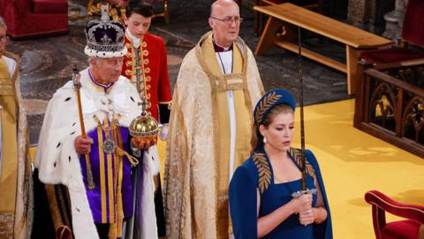Penny Mordaunt carrying a sword in front of King Charles during his coronation