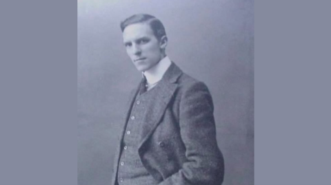 William Parr, with his hand in his double-breasted suit and shirt and tie, looks at the camera in this black and white photo