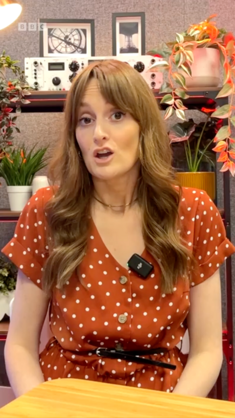 Harriet Robinson, a BBC journalist, sat at a table. She is looking into the camera.