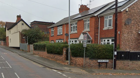 Houses front on to a road, with the road sign to the side of the end property saying Fowler Street