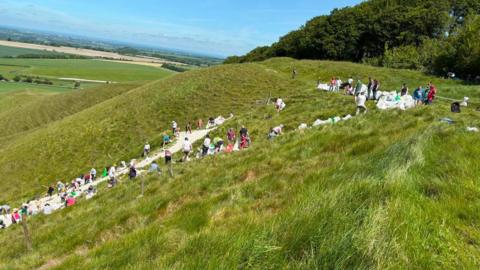 People on a hillside passing bags between them