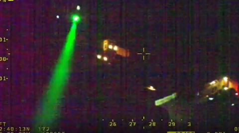 A picture shows darkness, with some lights from houses, and a green laser across the left of the picture. The top right of the picture says West Mercia Police.