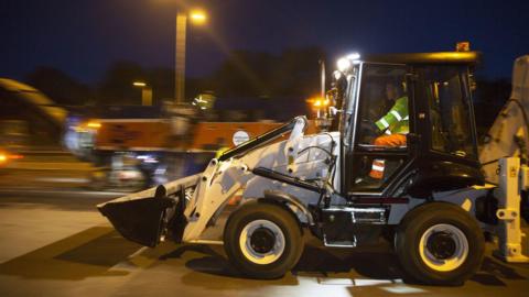 Work vehicles pictured on a main road late at night