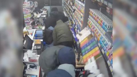 CCTV image of men raiding a shop.