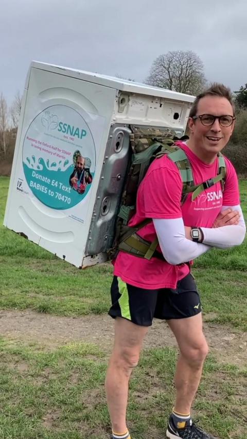 A man with a washing machine strapped to his back