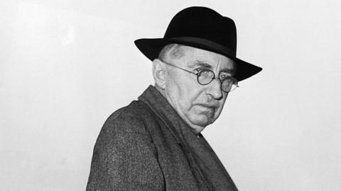 A man, EM Forster, in a coat and hat.