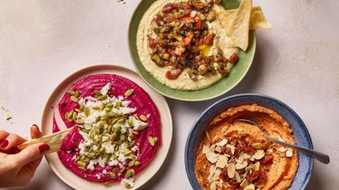 Three bowls of different types of hummus.