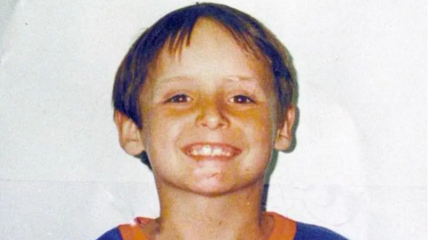 A smiling Wesley Neailey who has brown short hair and is wearing an orange and blue top.