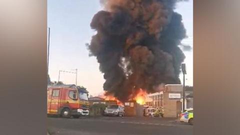 A fire at a building with a fire engine and police car in the area