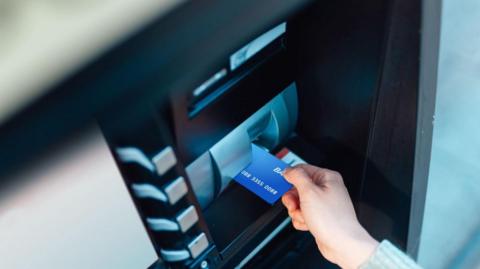 A person's hand putting a blue bank card into a card machine