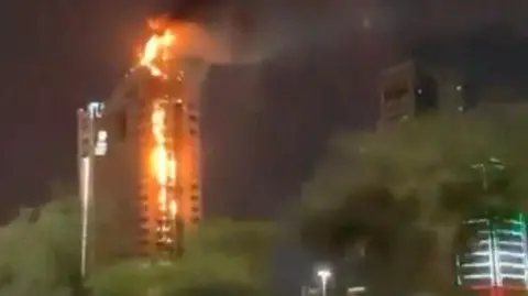 A large tower is shown with flames on the side