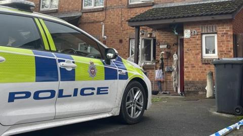 A police car parked in front of a brick house