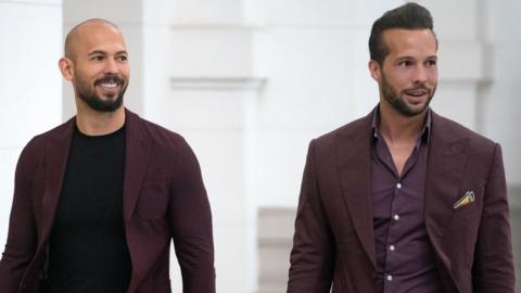 Andrew Tate (left) and his brother Tristan Tate walk inside the Court of Appeal in Bucharest, Romania, wearing maroon clothing.