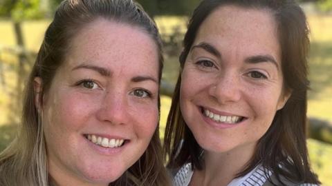 Two women in their thirties, Esme Sparks, who is blonde, and Lucy Sparks, who has dark hair. 
