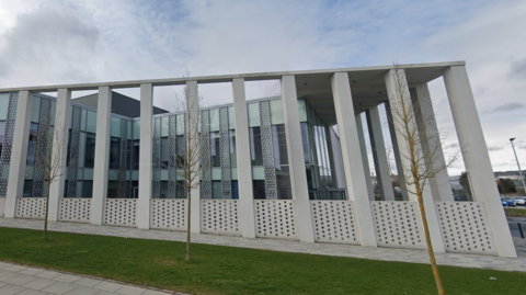 The grey exterior of Inverness Justice Centre. The outside of the building features a number of pillars.