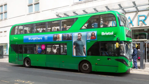 A green First Bus in Bristol outside a Primark store with an Amazon Prime advert on the bus.