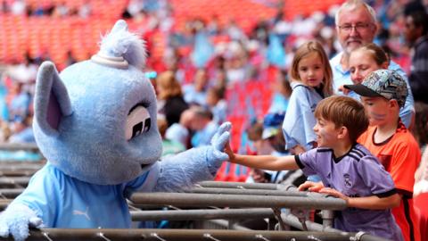 Man City mascot high fives a child
