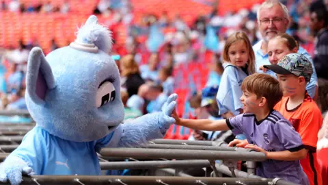 Man City mascot high fives a child