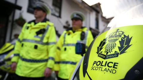 Police seen standing in fluorescent uniform next to a motorbike