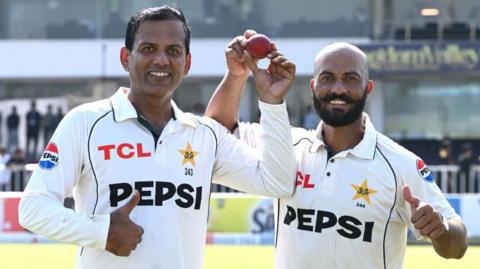 Pakistan spinners Noman Ali (left) and Sajid Khan (right) hold up the ball together as they walk off after dismissing England