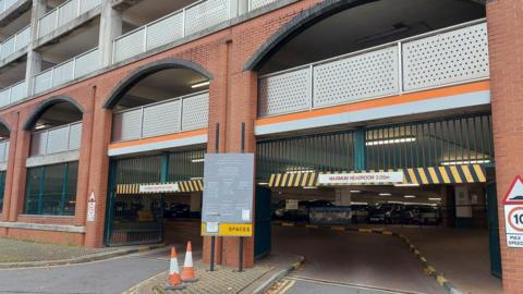 A multi-story car park entrance with cones and a maximum headroom sign of 2.05 metres.