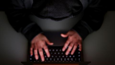A laptop user with their hood up.