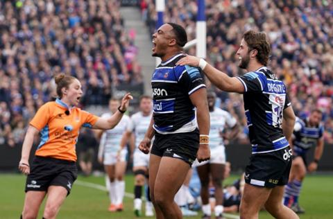 Bath players celebrate a try scored against Gloucester at the Rec. The female referee, wearing an orange top, is signalling the try