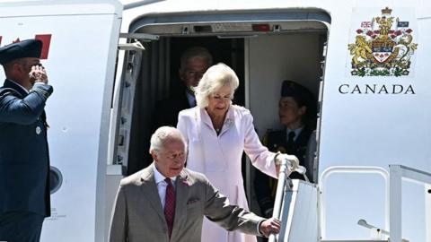 King Charles and Queen Camilla walking down the stairs of a plane  Macdonald-Cartier International Airport in Ottawaat 