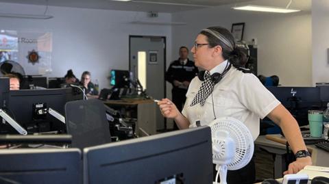 Jersey police control room with officers working at computers.
