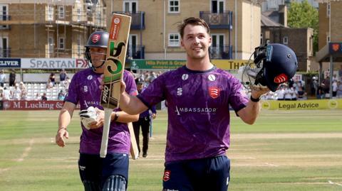 Curtis Campher raises is bat and helmet to acknowledge applause for his century for Essex against Surrey