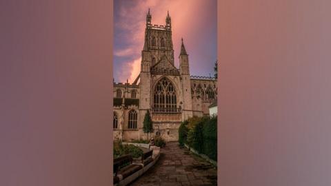 Gloucester Cathedral in front of a pink sky.