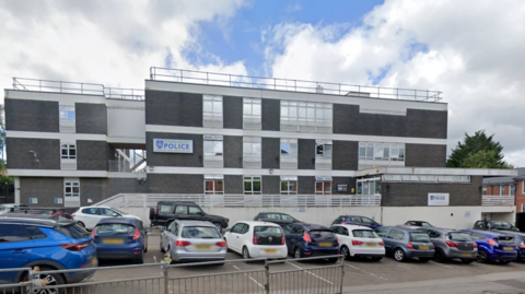 A Google Maps picture of Cowley police station, a three storey office building with about 20 cars parked outside it.