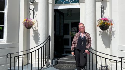 Jess Fry standing on steps in front of a white brick building