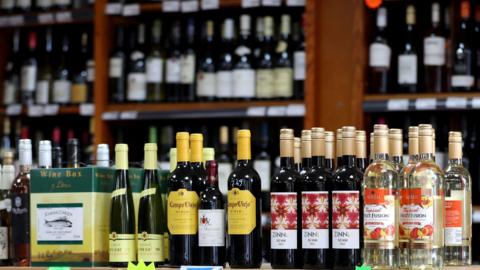 A wine shop with bottles of wine on a shelf and more shelves of wine in the background