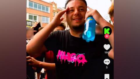 A man holds his hands to his head as large crowds follow behind him in Norwich city centre, taken from a TikTok screenshot