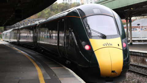 A GWR train pulls into Bristol Temple Meads station, its carriages are green with a yellow rectangle on the nose.