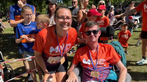Craig and Ileshia Eskrett wearing training tops surrounded by support for the Run For MND