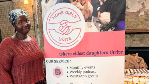 Co-founder Yasin stands next to a ˿ Girls Unite poster